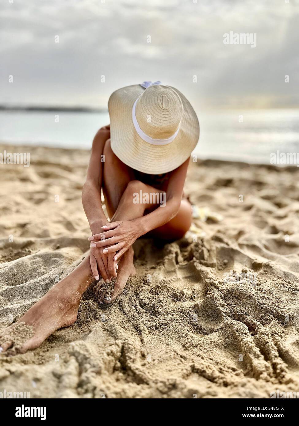 Junge Frau mit Sommerhut am tropischen Strand - Smartphone-aufgenommenes Stockfoto
