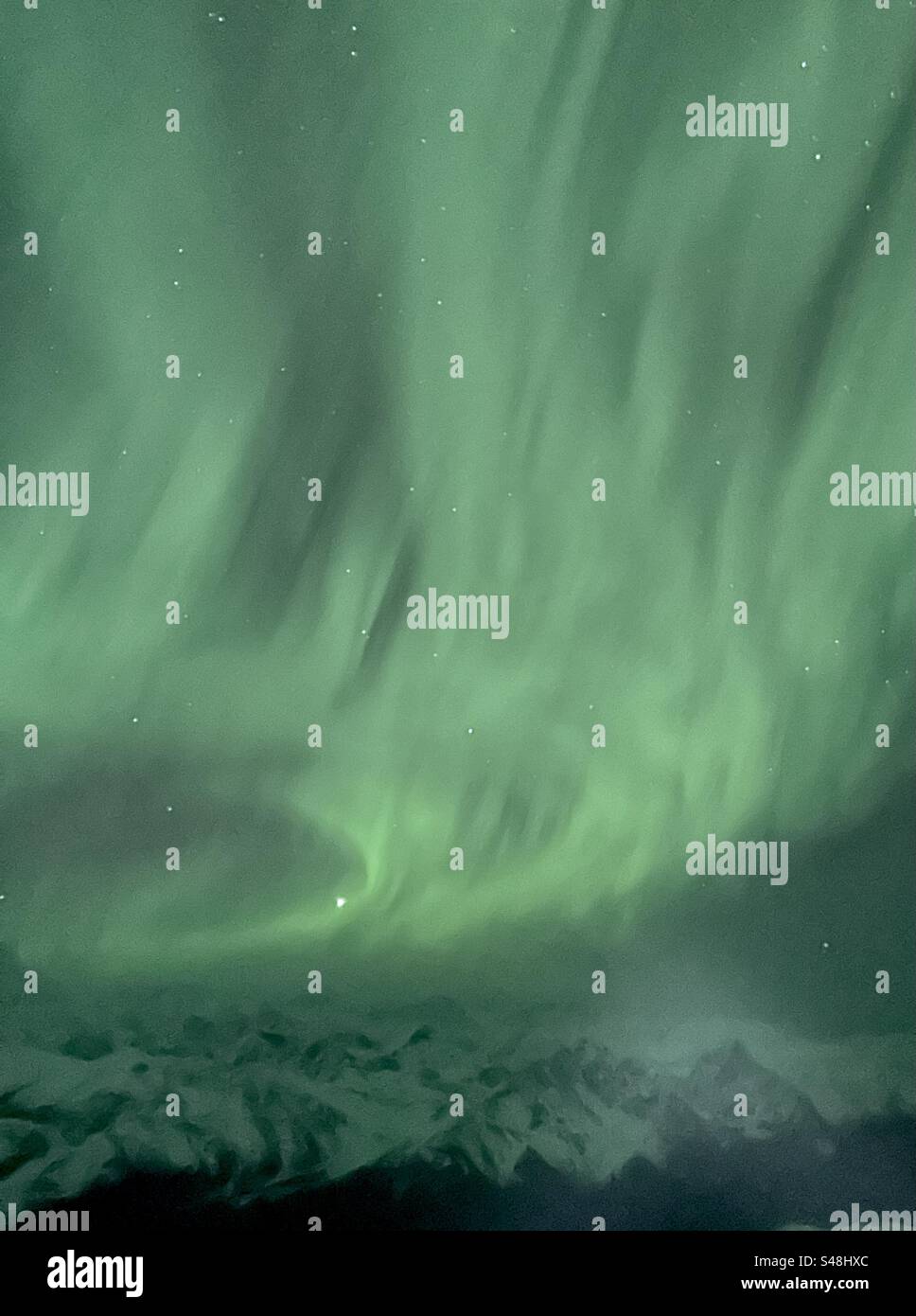 Nordlichter über den Bergen Alaskas aus der Luft. - Smartphone-aufgenommenes Stockfoto