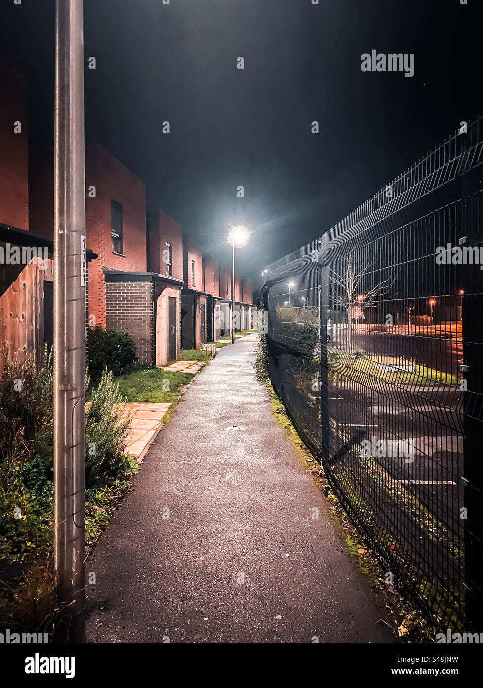 Spaziergang entlang eines Weges vorbei an modernen Stadthäusern bei Nacht. Stockfoto