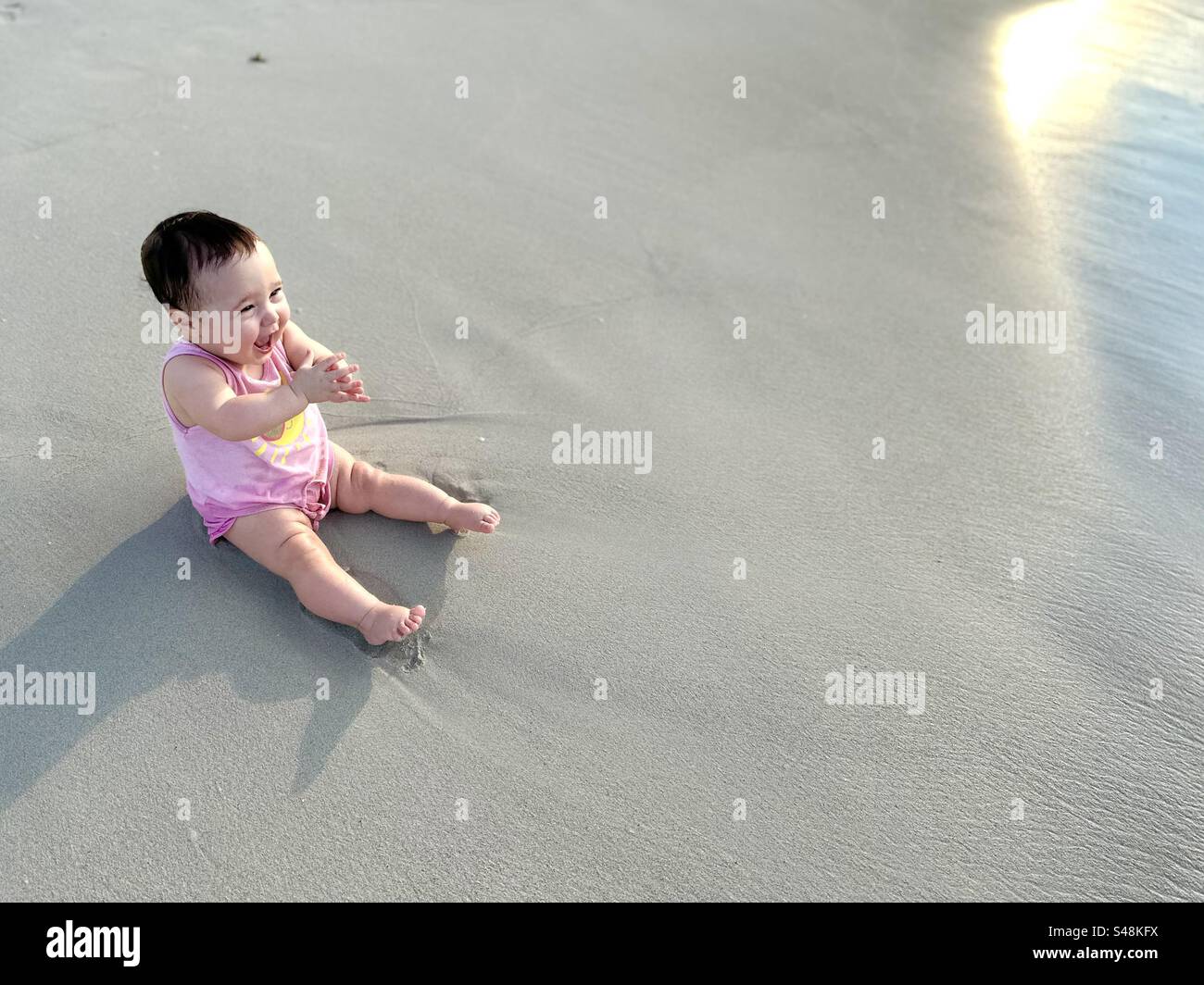 Baby klatscht mit Spannung am Strand von Varadero, Kuba - Smartphone-aufgenommenes Stockfoto