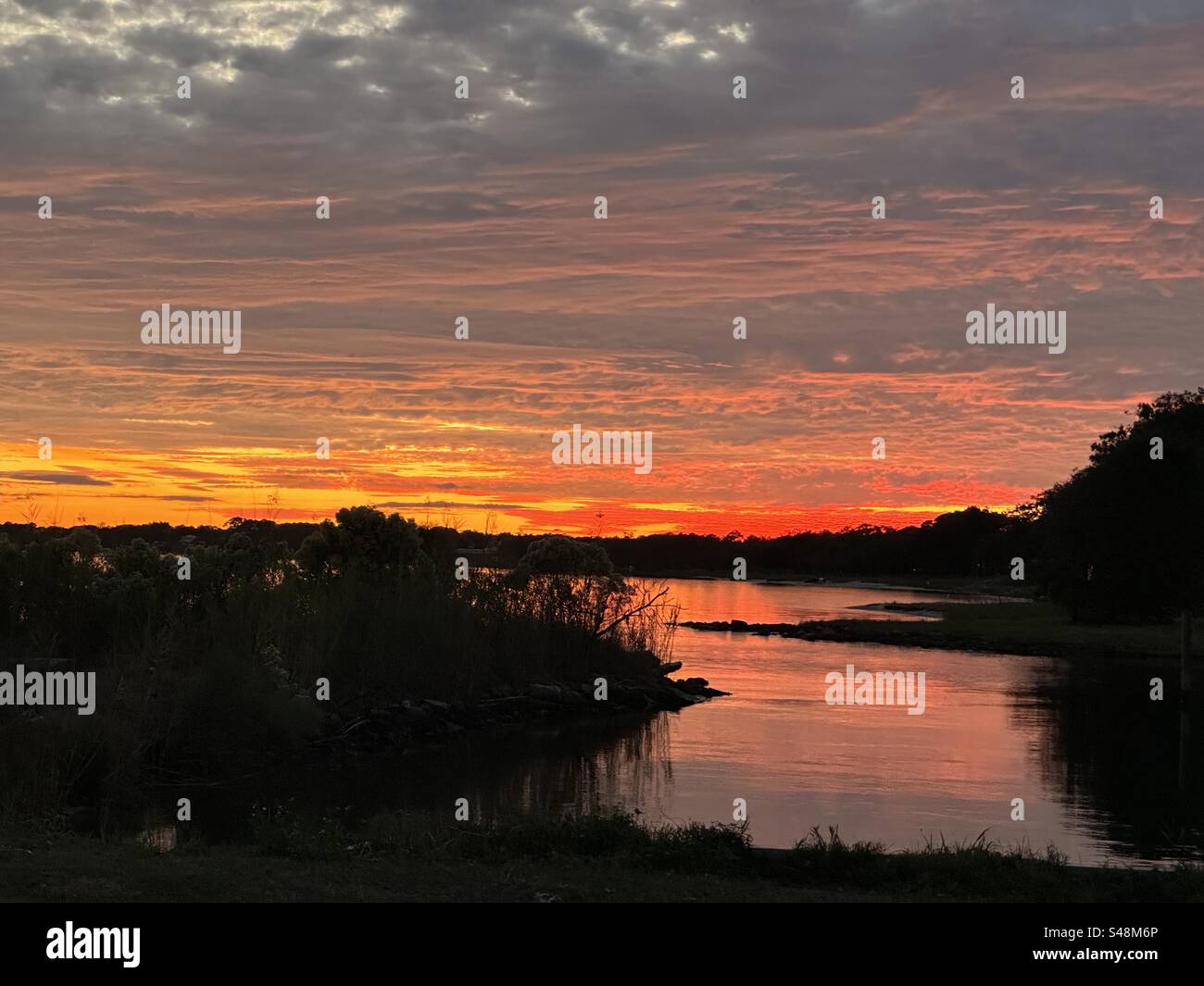 Ein strahlender Sonnenuntergang, den er von der Vorderseite des Bildes bis ganz nach hinten ausstrahlt. Eine herrliche Aussicht auf die Bucht!! Stockfoto