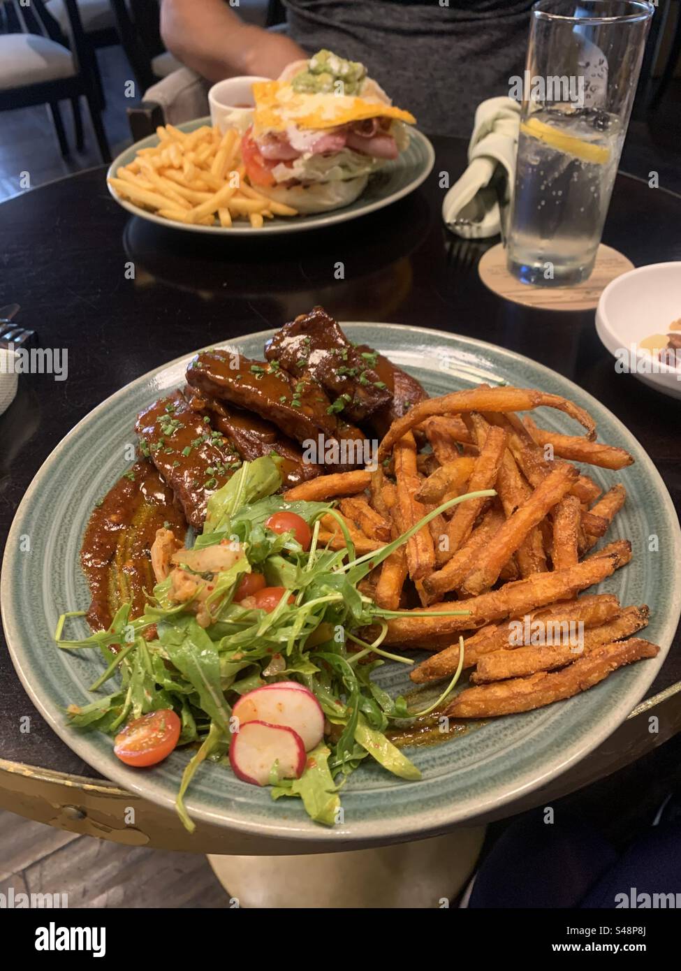 Baby-Back-Schweinerippchen mit Süßkartoffelfritten und Kimchi-Salat, serviert in einem Gastropub Stockfoto