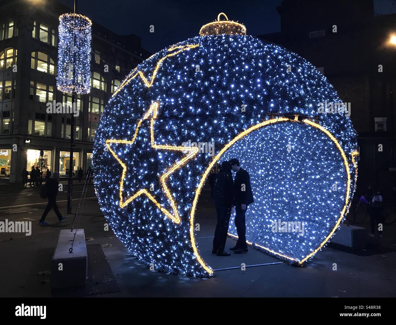 Ein Paar hält Hände in einer Weihnachtsdekoration in London - Smartphone-aufgenommenes Stockfoto