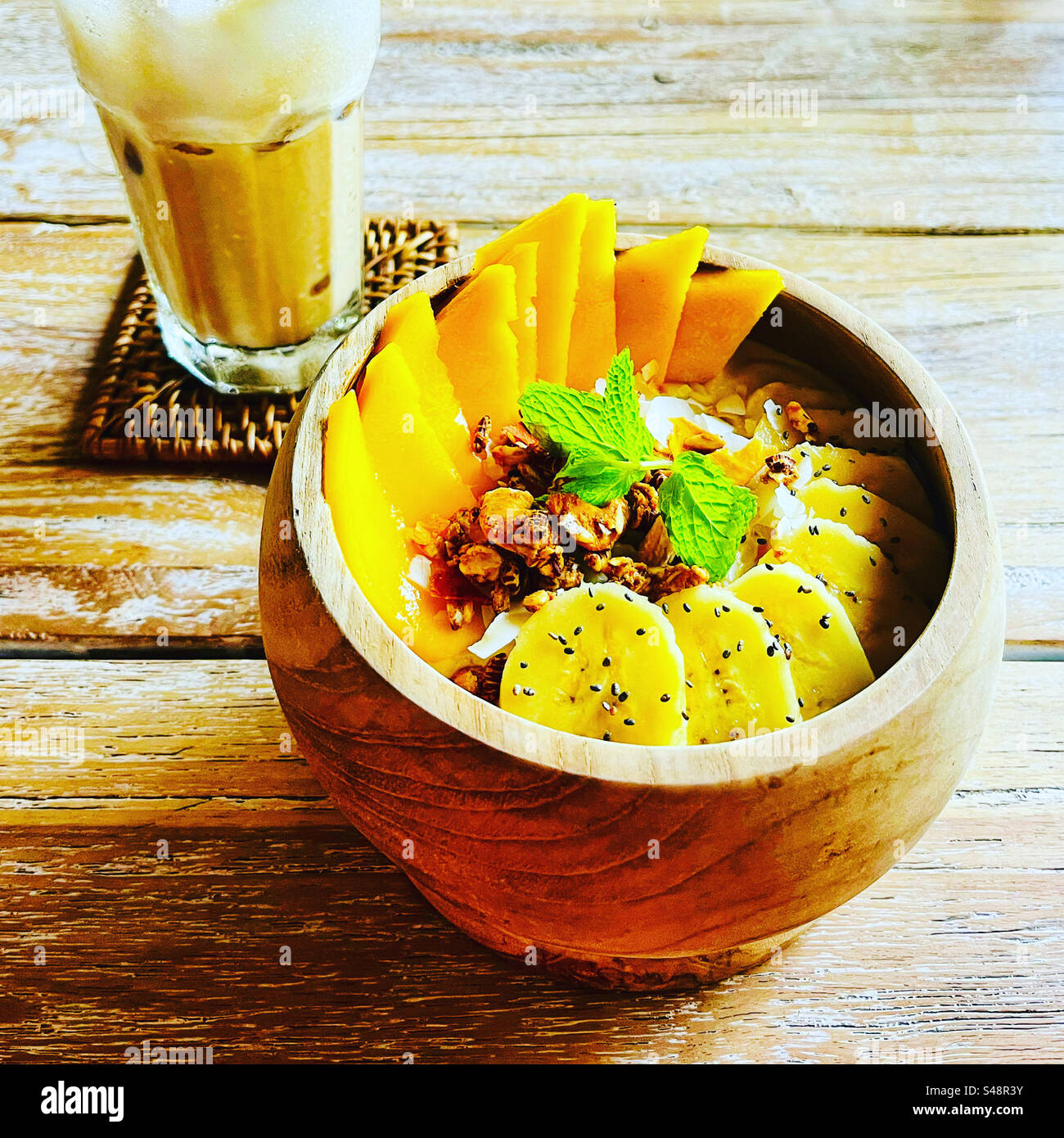 Frühstück einer tropischen Smoothie Schüssel mit Banane und Mango und einem Eiskaffee auf Bali Indonesien Stockfoto