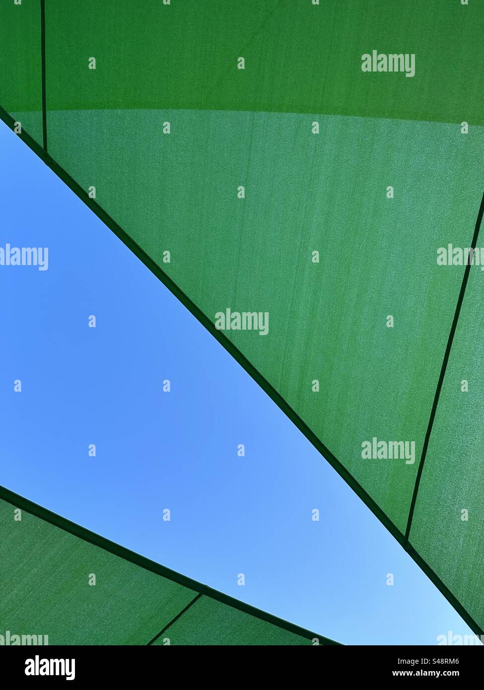 Abstrakter Hintergrund mit Blick auf den blauen Himmel durch grünen Stoff im Freien Stockfoto