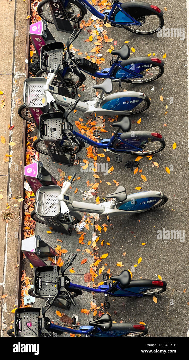 Blick von High Line Elevated Walk auf Citi Bikes, wo sie in ihren Wiegen auf einer Straße voller Herbstlaub gemietet werden. - Smartphone-aufgenommenes Stockfoto