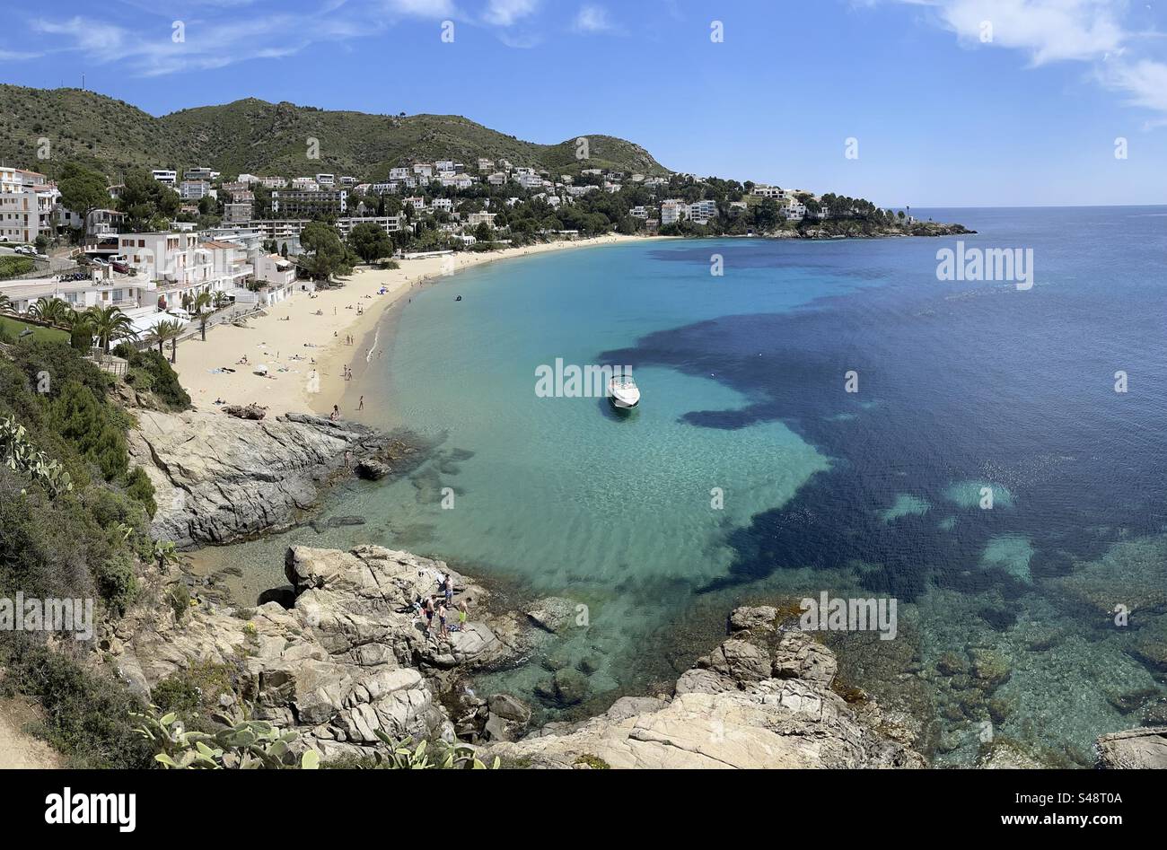 Panoramablick auf den östlichen Strand calanque mit einem Boot vor Anker in Roses, Costa Brava, Spanien Stockfoto