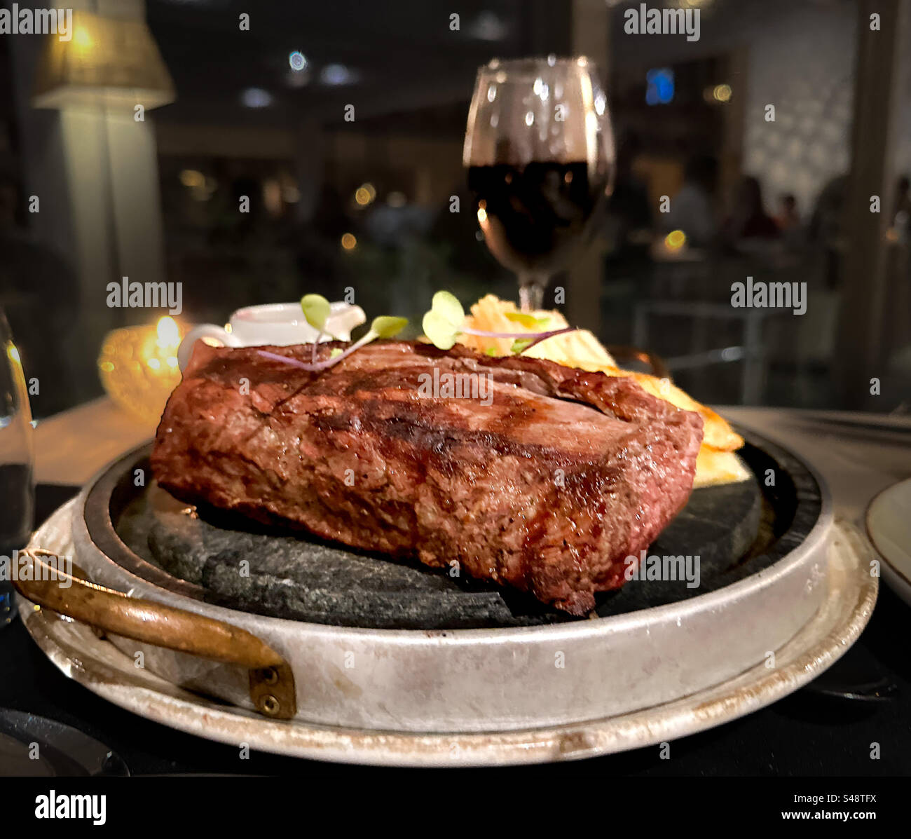 Teller mit brutzelndem Rindfleisch in einem schicken Restaurant - Smartphone-aufgenommenes Stockfoto