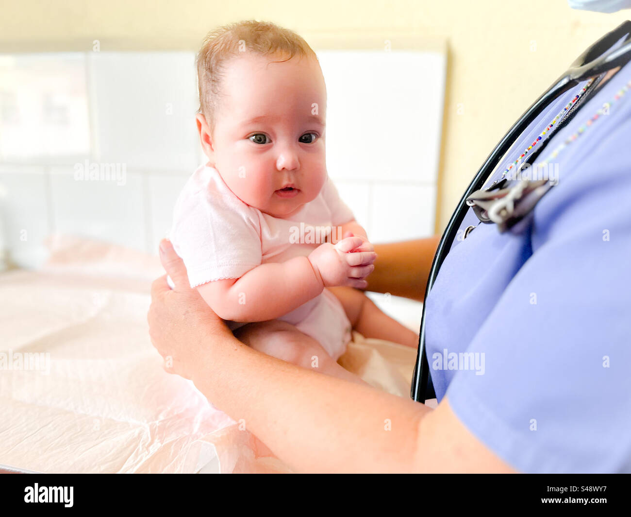 Baby, das bei einem Kindertermin von einer Ärztin festgehalten wird Stockfoto
