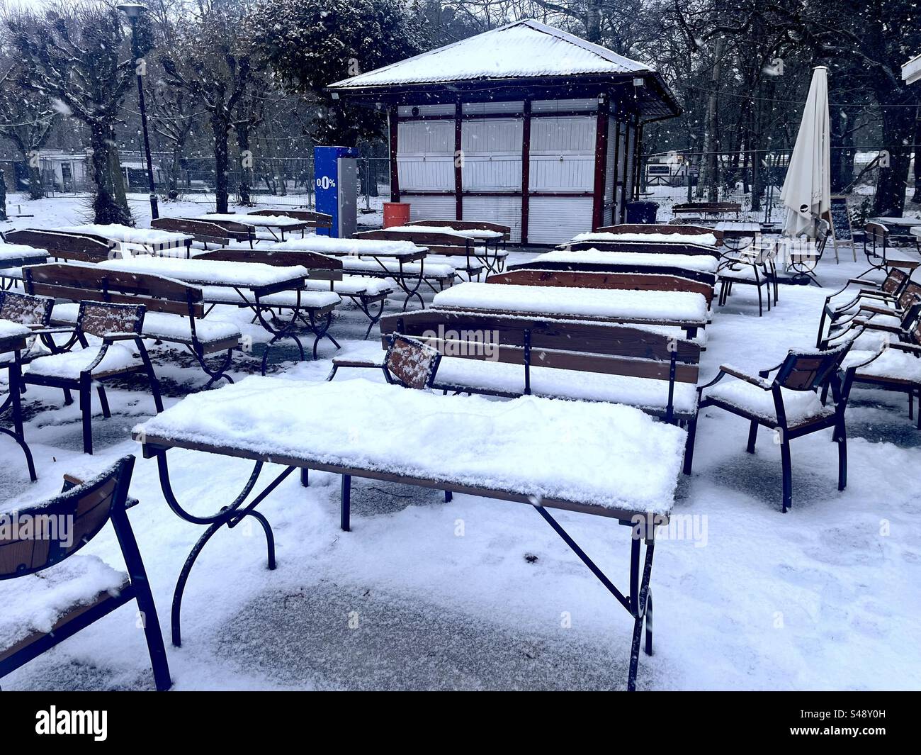 Außerhalb der Saison in einem geschlossenen Café im Jelitkowski Park, Danzig, Polen, Europa, EU, Tische und Stühle im Freien mit Schnee bedeckt - Smartphone-aufgenommenes Stockfoto