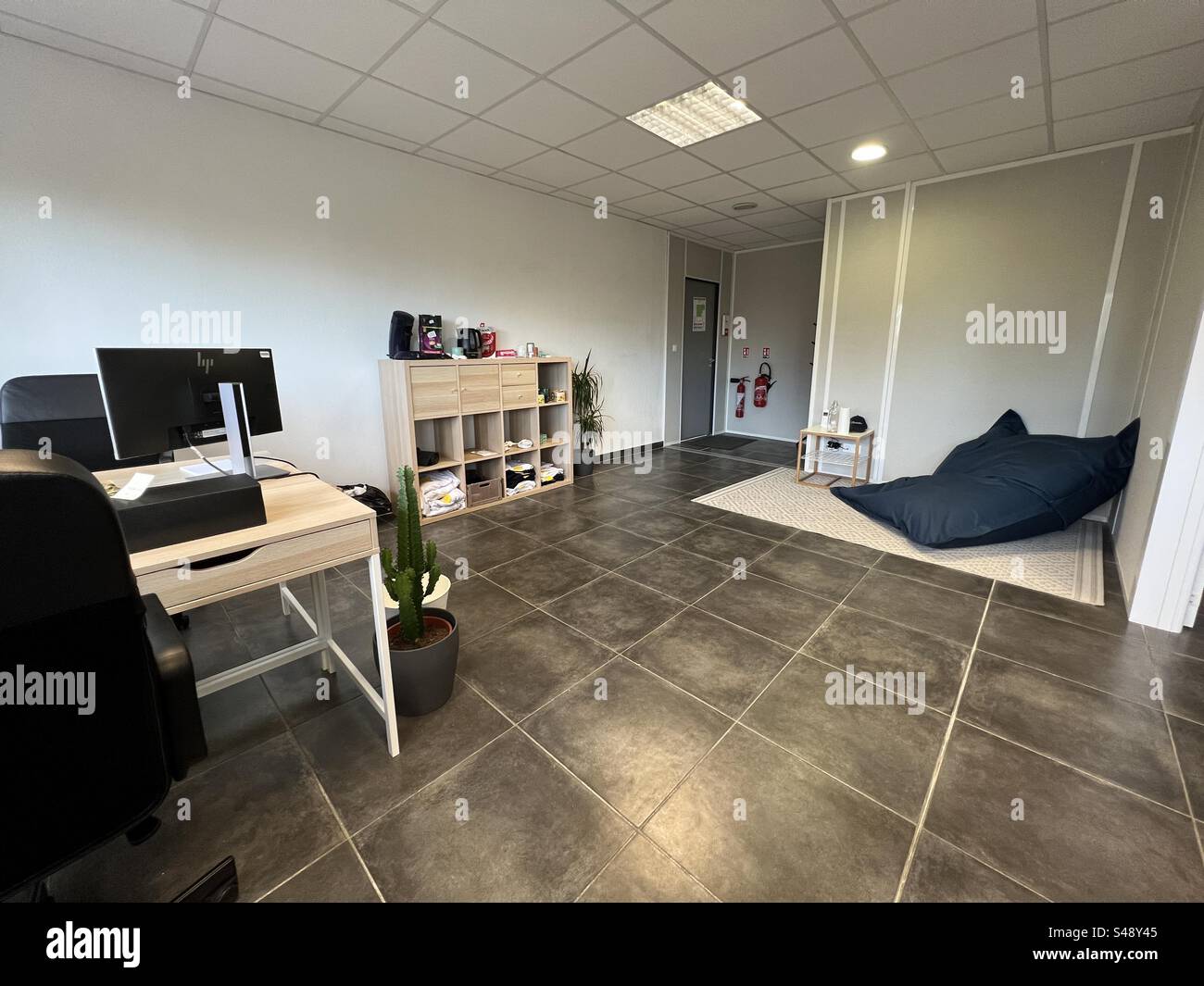 Innenaufnahme eines Büros im offenen Stockwerk mit Tischstühlen, Möbeln und Boden-Sandsacksitz. Stockfoto