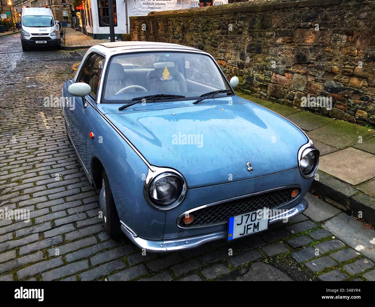 Nissan Figaro Auto im Retro-Stil parkt auf der Straße - Smartphone-aufgenommenes Stockfoto