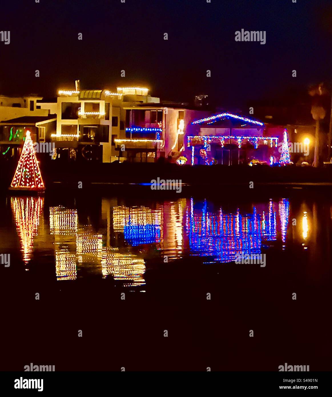 Weihnachtslichter und ein schwimmender „Weihnachtsbaum“ und ihre Reflexionen in der Alamitos Bay zwischen Neapel und der Halbinsel (Long Beach, Kalifornien) während der Weihnachtszeit 2023. Stockfoto