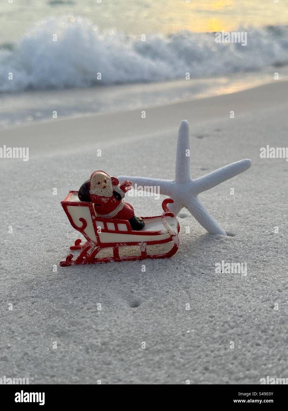 Santa Claus im Schlitten mit einem Seestern auf Strandsand Stockfoto