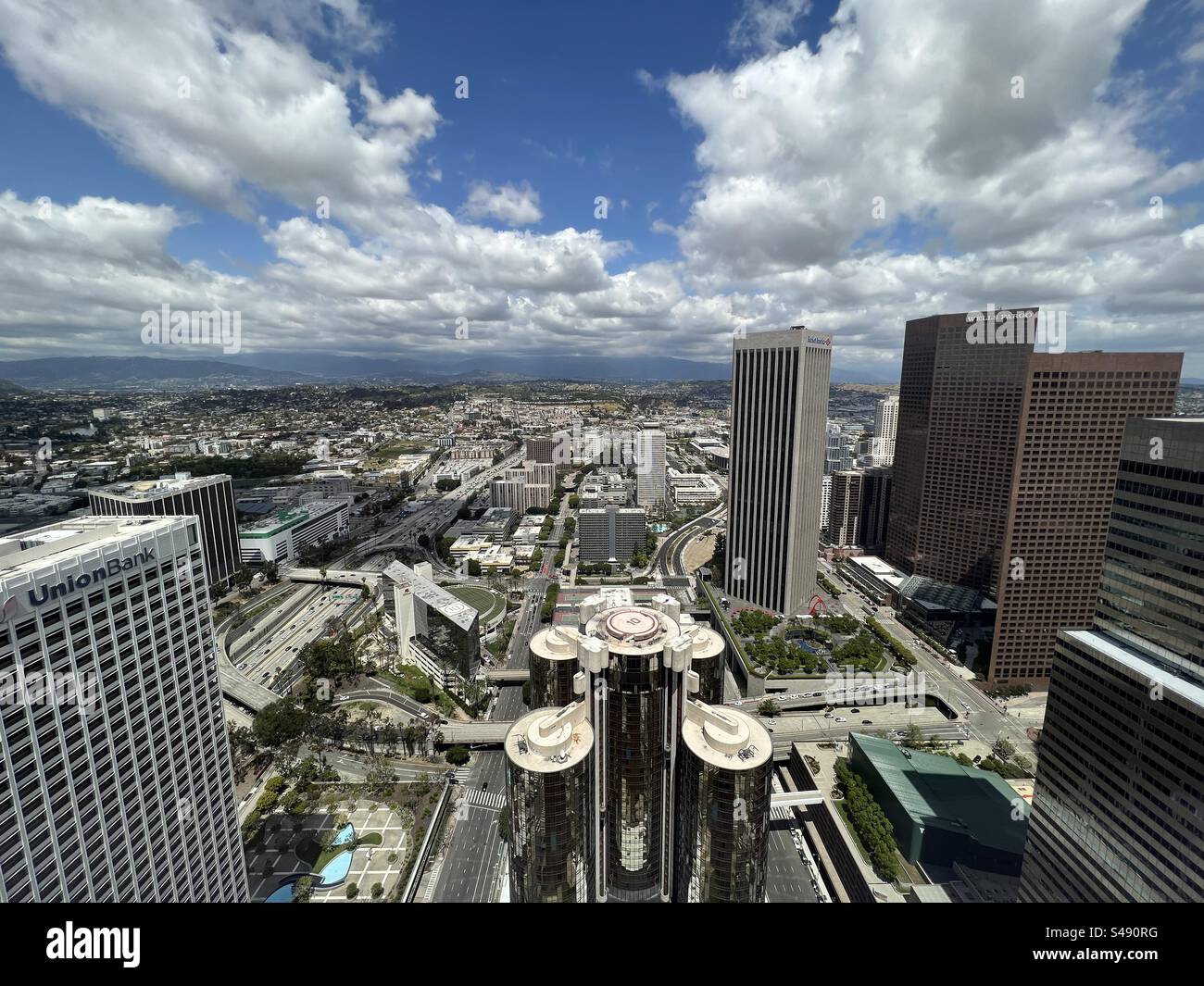 LOS ANGELES, CA, MAI 2023: Weitwinkelblick aus der Luft, Blick über das Westin Bonaventure Hotel, in Richtung Finanzviertel der Innenstadt, weit entfernte Berge im Hintergrund. Stockfoto