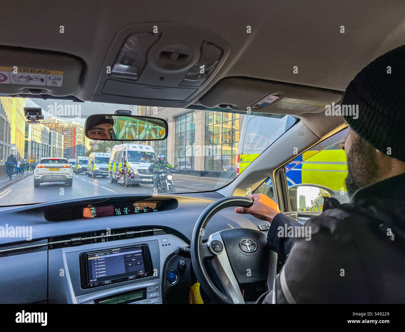 Uber Taxifahrer, der an einer Polizeieskorte in Leeds vorbeifährt Stockfoto