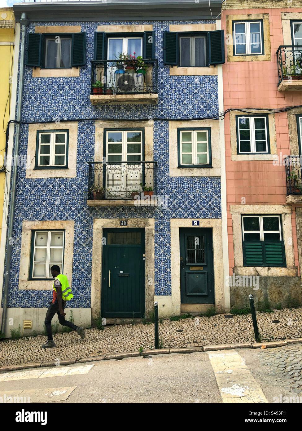 Lissabon, Portugal - 13. September 2024: Traditionelles portugiesisches Gebäude mit blauen Azulejo-Fliesen, Balkonen und grünen Fensterläden auf einem schrägen Kopfsteinpflaster - Smartphone-aufgenommenes Stockfoto