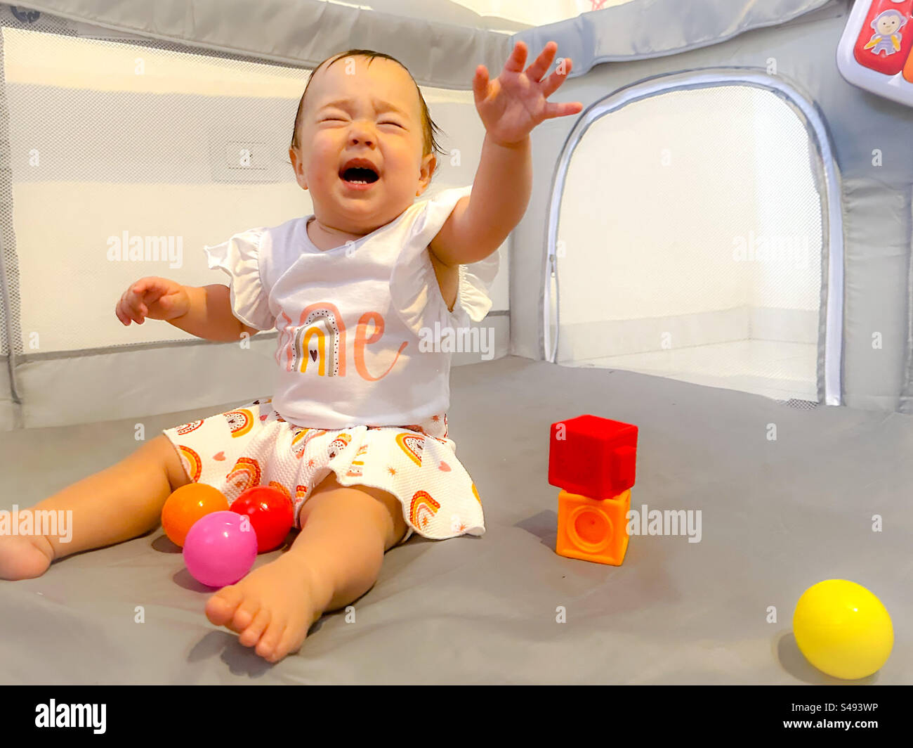 Ein Jahr alter Mädchengeburtstag. Regenbogenbaby-Motive. Das Baby hört auf, aufgeregt zu sein Stockfoto