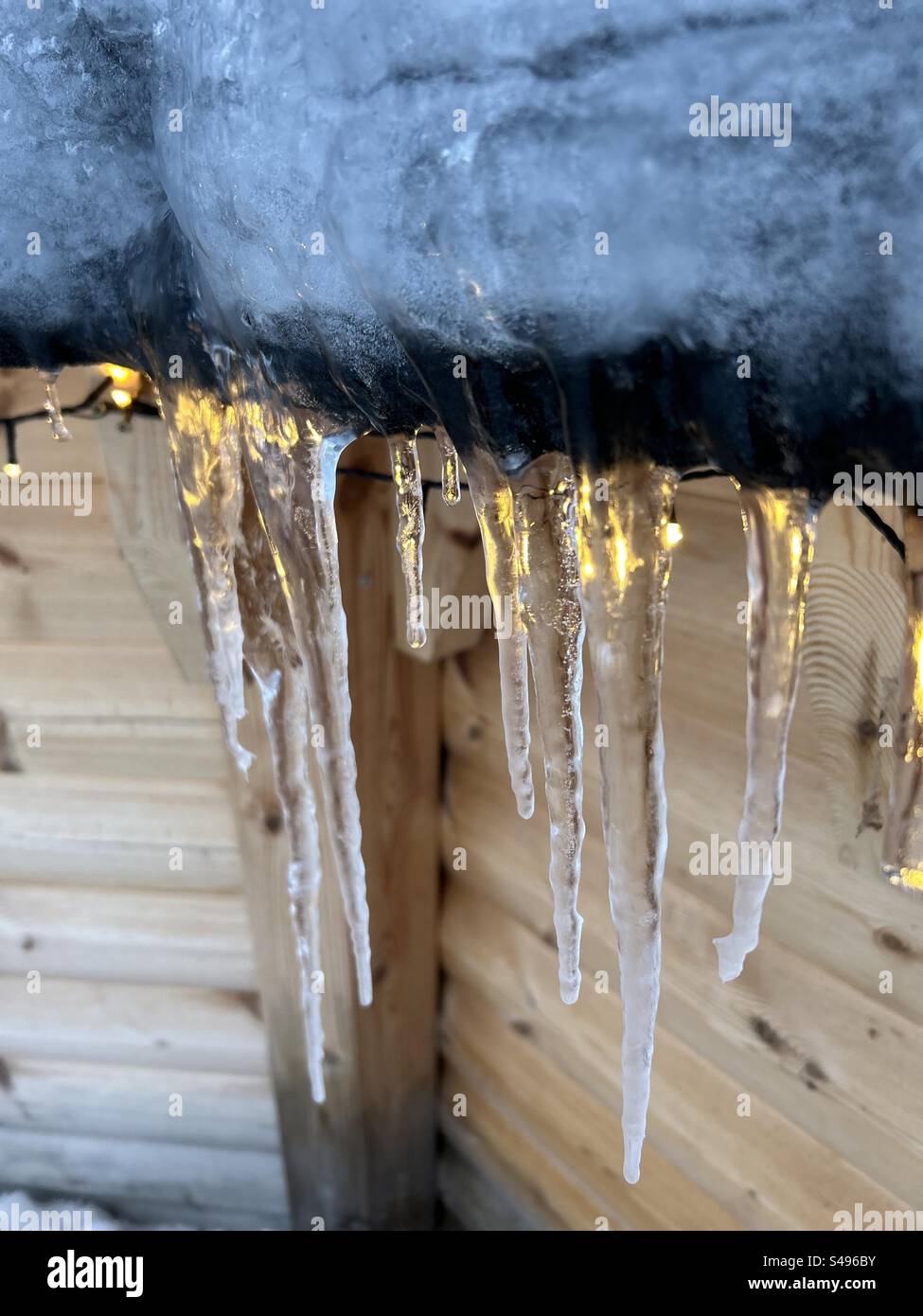 Eiszapfen hängen von einem niedrigen Dach Stockfoto