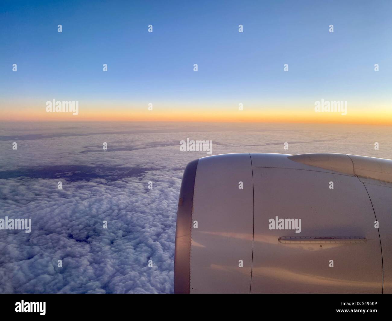 Sonnenaufgang über den Wolken im Triebwerksflugzeug Stockfoto