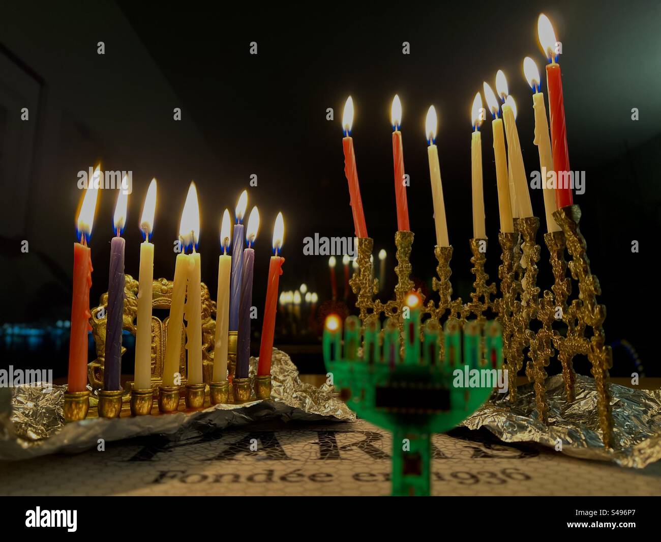 Drei Hanukkah-Menorahs werden in der letzten Nacht des Lichterfestes hell beleuchtet. - Smartphone-aufgenommenes Stockfoto