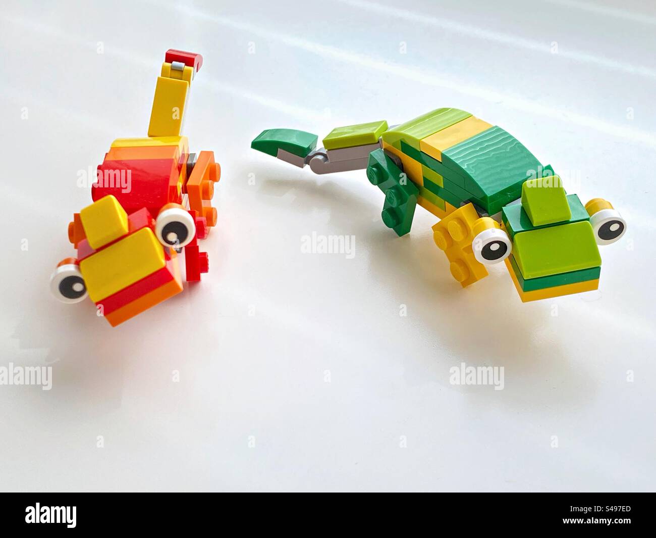 Ein Paar Chamäleons aus Kunststoffziegeln stehen auf weißem Hintergrund. Stockfoto