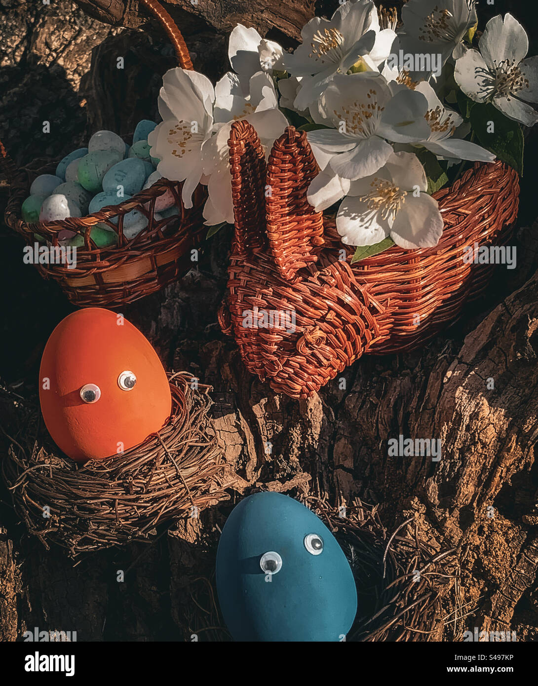 Eier in Nestern mit kaninchenförmigem Blütenkorb - Smartphone-aufgenommenes Stockfoto