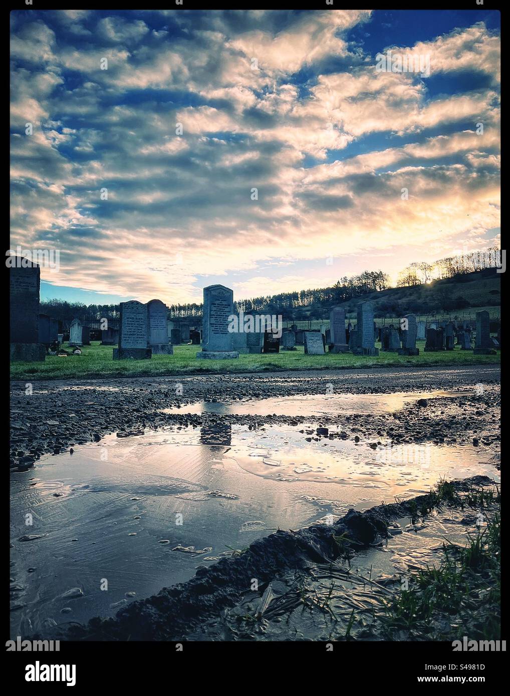 Friedhof an einem kalten Tag mit Reflexionen in eisigen Pfützen. Stockfoto