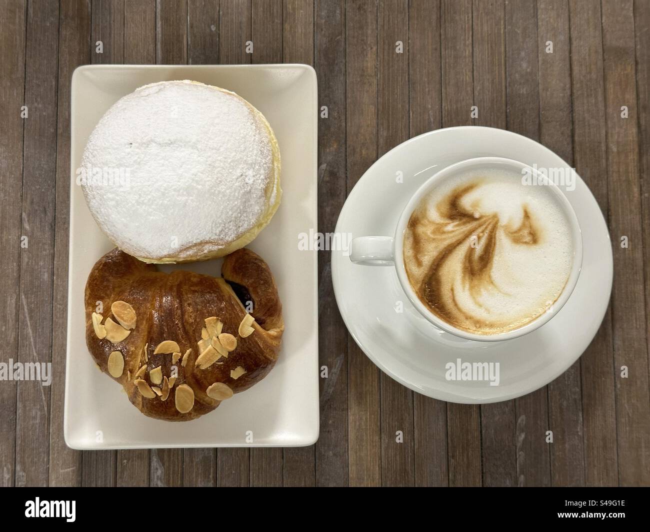 Reichhaltiges Frühstück an der Bar mit Cappuccino, Croissant und krapfen Stockfoto