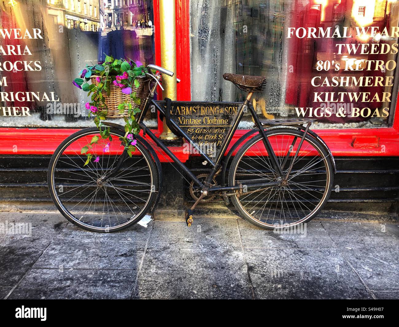 Fahrradladen im alten Stil, in dem Armstrong & Son Vintage-Kleidung, Tweeds, Kaschmir, Kiltwear, Grassmarket Edinburgh Schottland angeboten wird Stockfoto