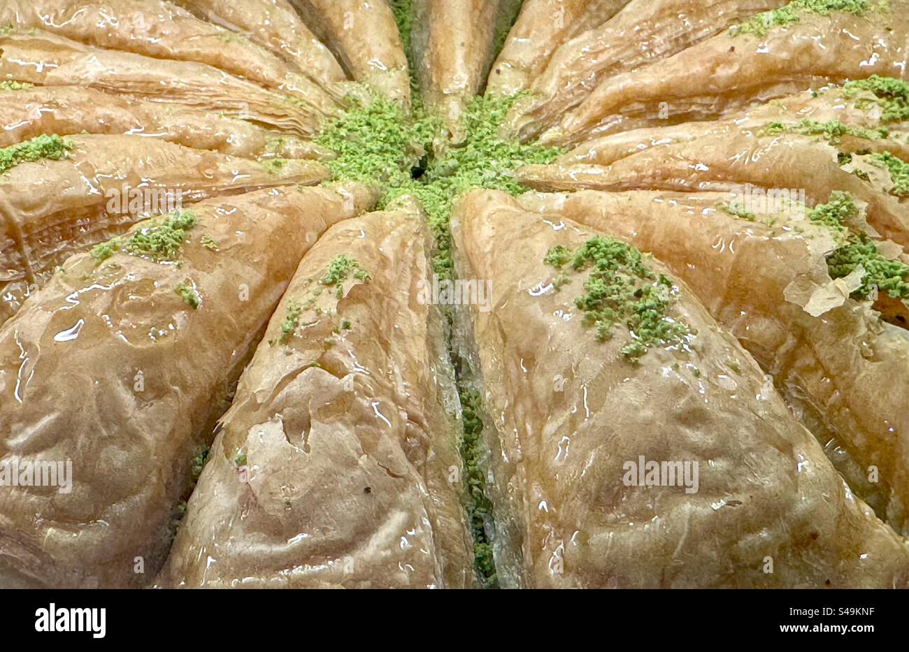 Nahaufnahme traditioneller griechischer Baklava aus Phyllo-Teig, zerstoßenen Nüssen und eingeweicht in Honigsirup, garniert mit zerstoßenen Pistazien. Stockfoto