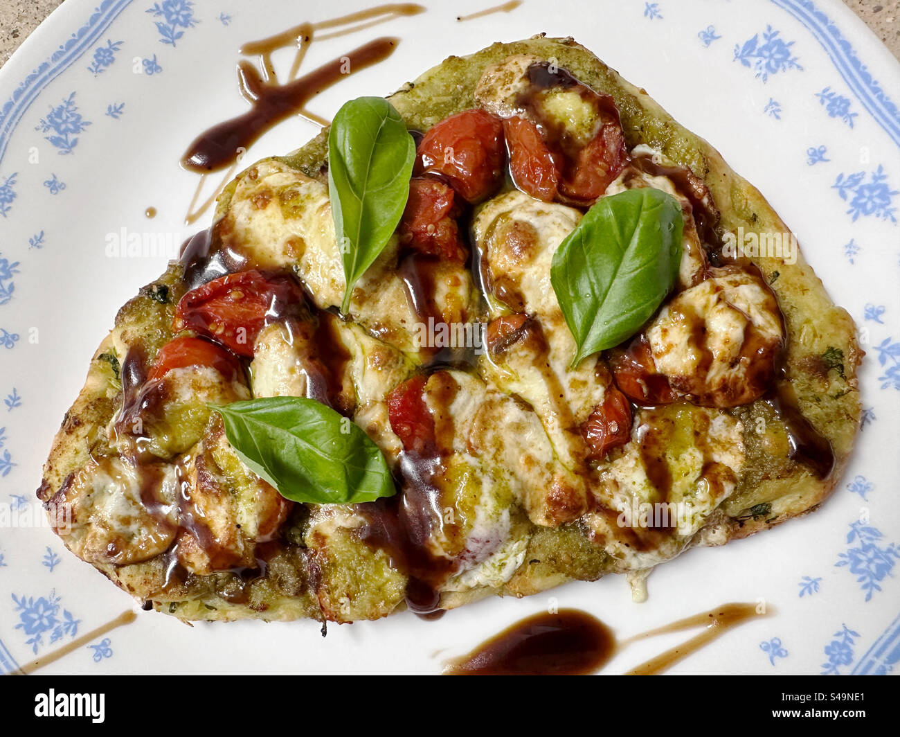 Caprese Fladenbrot – Tomaten, Pesto-Sauce, frischer Mozzarella, Zwiebeln und Basilikumblätter auf Naan-Brot und mit Balsamico-Glasur getränkt. Stockfoto