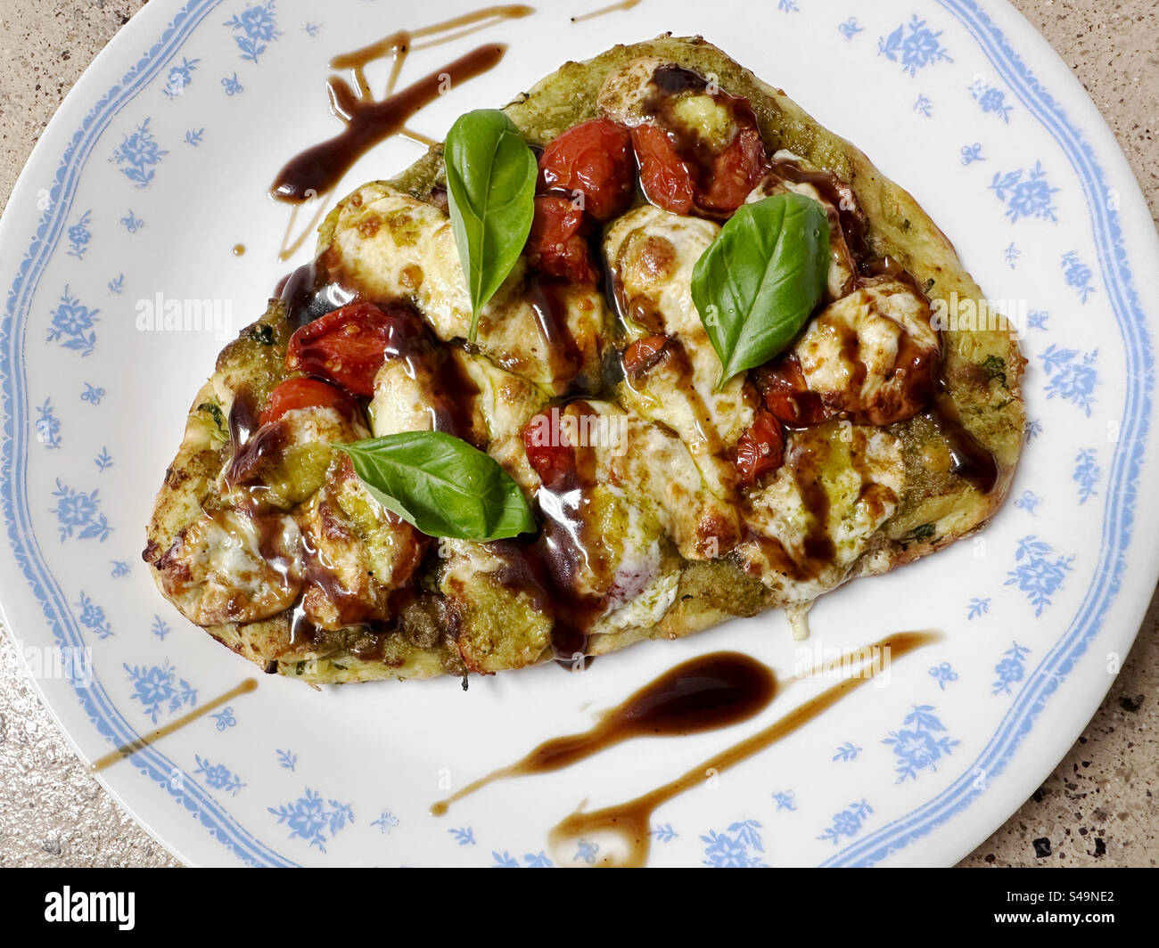 Caprese Fladenbrot – Tomaten, Pesto-Sauce, frischer Mozzarella, Zwiebeln und Basilikumblätter auf Naan-Brot und mit Balsamico-Glasur getränkt. Stockfoto