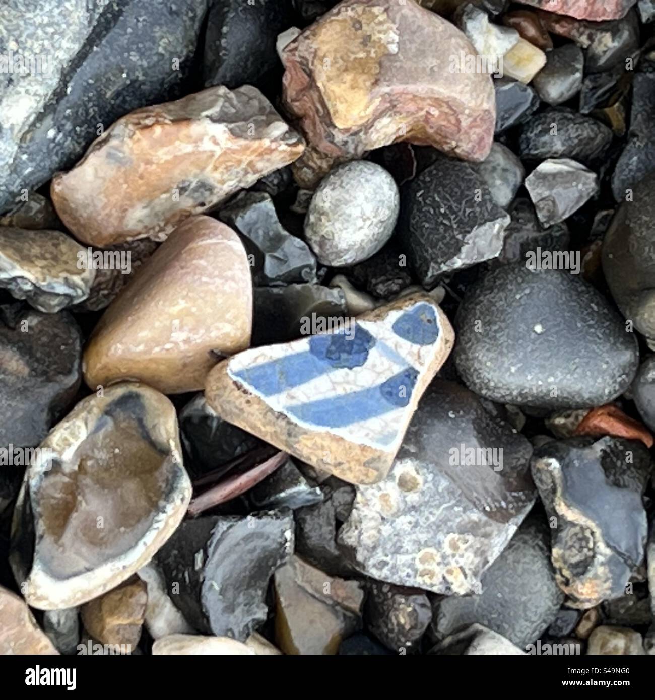 Delftware-Töpferstück gegen Felsen an der Themse vor London von lizenziertem Mudlark - Smartphone-aufgenommenes Stockfoto