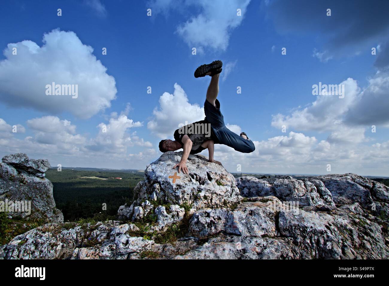 Mann in Breakdance-Position auf einem Felsen Stockfoto