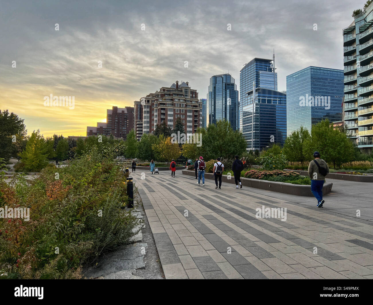 Menschen, die bei Sonnenaufgang in Calgary, Alberta, Kanada, am Prince’s Island Park zur Arbeit gehen. - Smartphone-aufgenommenes Stockfoto