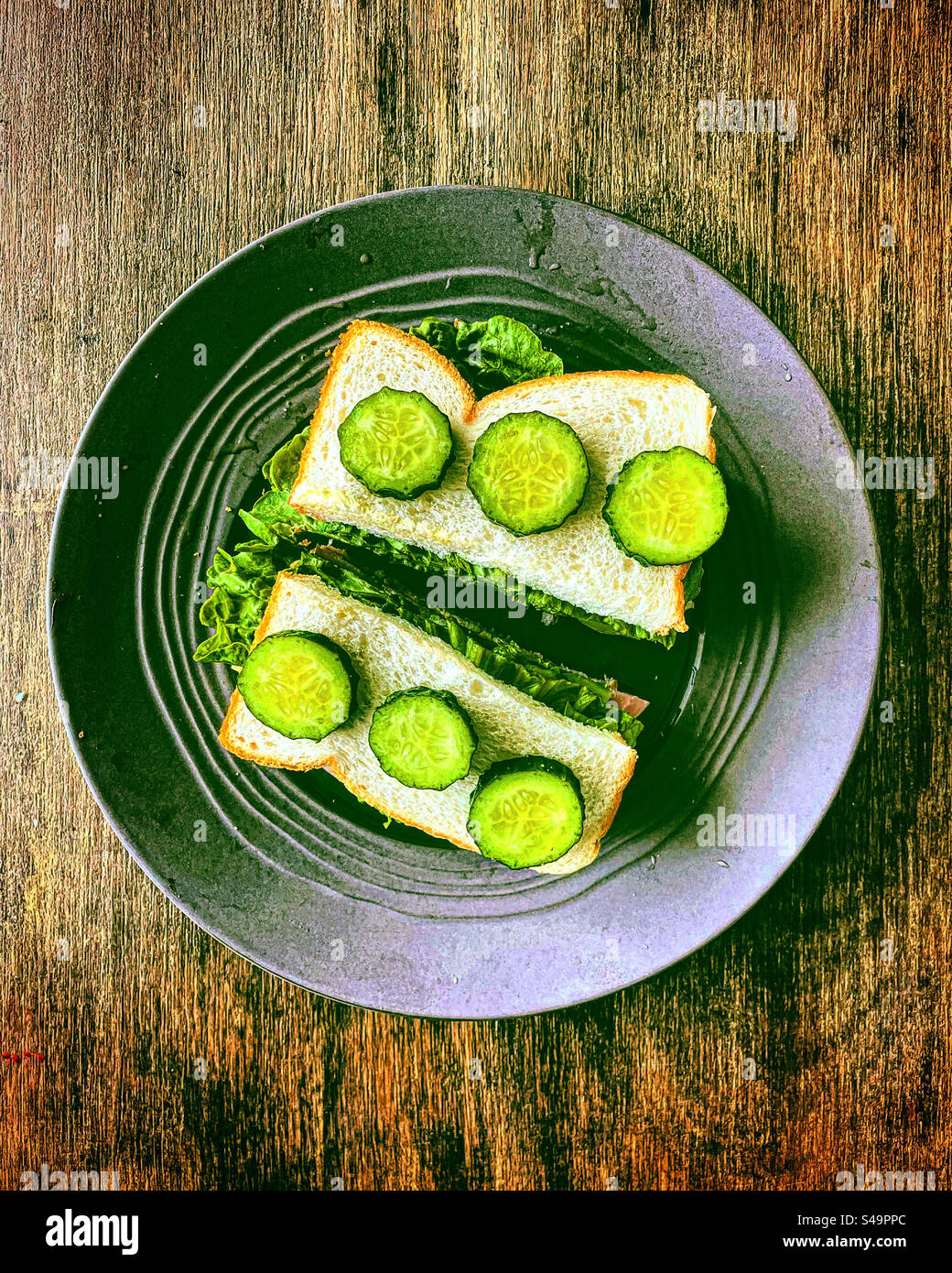 Man hatte auch einen Blick auf ein Salatsandwich mit Gurkenscheiben als Snack-Diner-Abendessen, das von einem Koch oder einer Mutter für ihr Kind zubereitet wurde - Smartphone-aufgenommenes Stockfoto