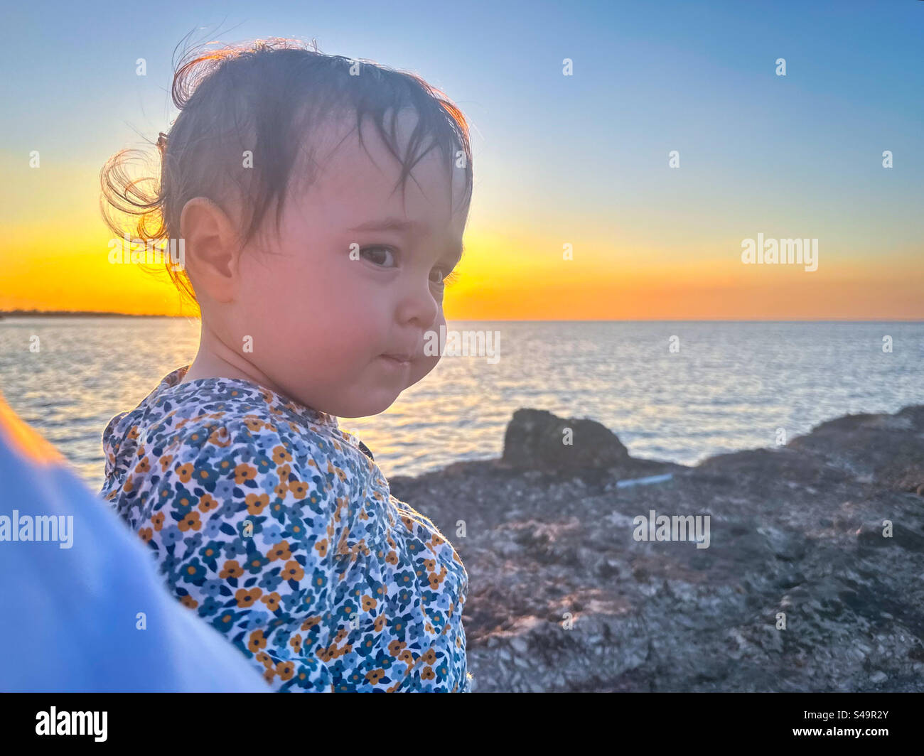 Baby am Meer bei Sonnenuntergang - Smartphone-aufgenommenes Stockfoto