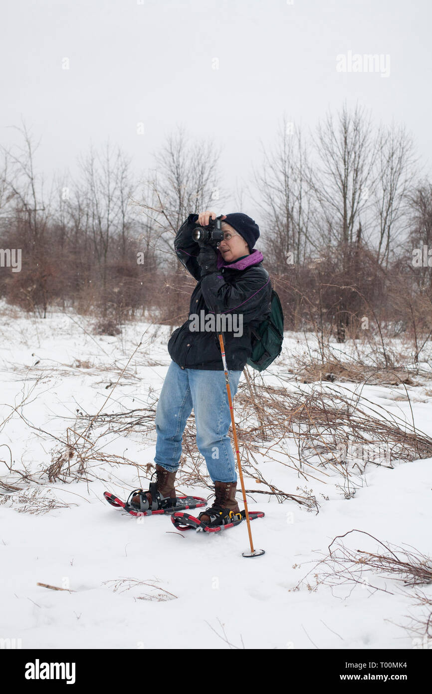 Frau Fotograf Shooting im Winter mit Schneeschuhen. Stockfoto