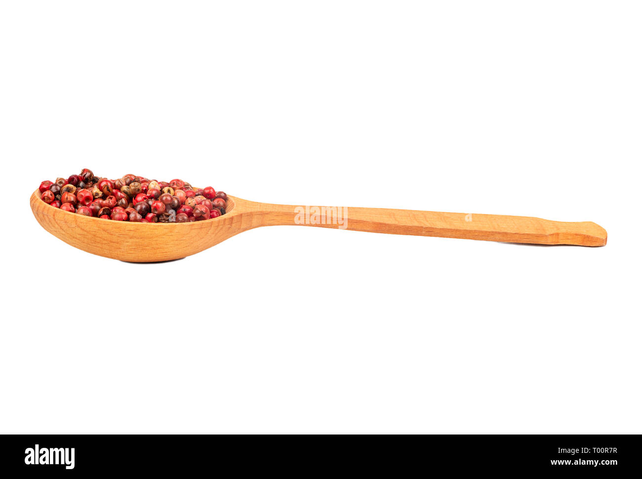 Rote Paprika Erbsen in einem Löffel aus Holz, auf einem weißen Hintergrund Stockfoto