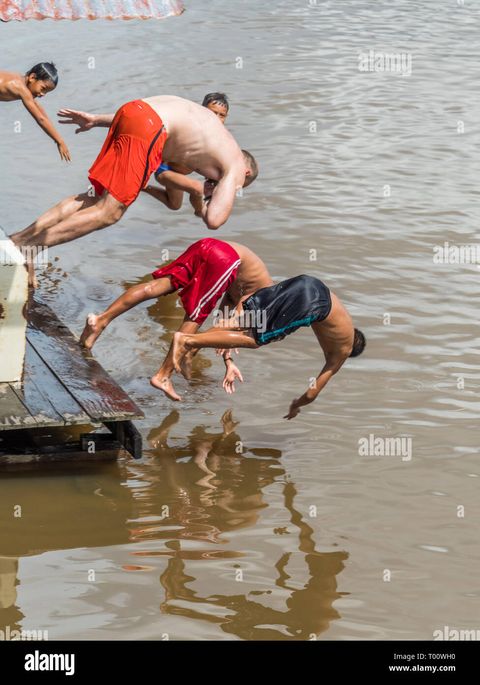 Pebas, Peru - Dezember 04, 2018: peruanische Kinder springen auf das Amazon Rover mit Weiß, großer Mann. Diversity Konzept Stockfoto