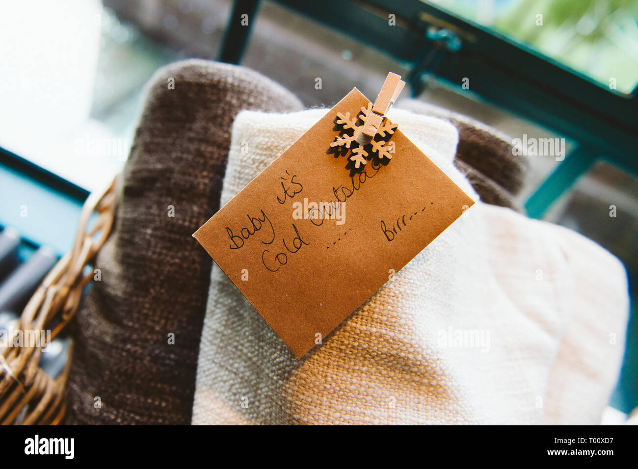 Eine Auswahl von Decken in einem Weidenkorb mit einem handschriftlichen Tag/Label außerhalb sagen Baby It's Cold Stockfoto