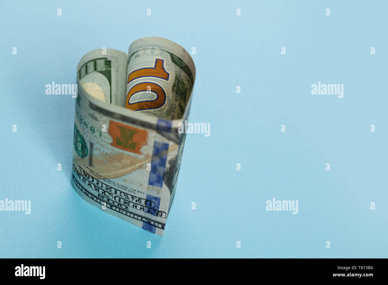 Win-win und kommerzielle Geldanlage gewinn Konzept. 100 US-Dollar Bargeld Bank Note Herzform auf blauem Hintergrund Stockfoto