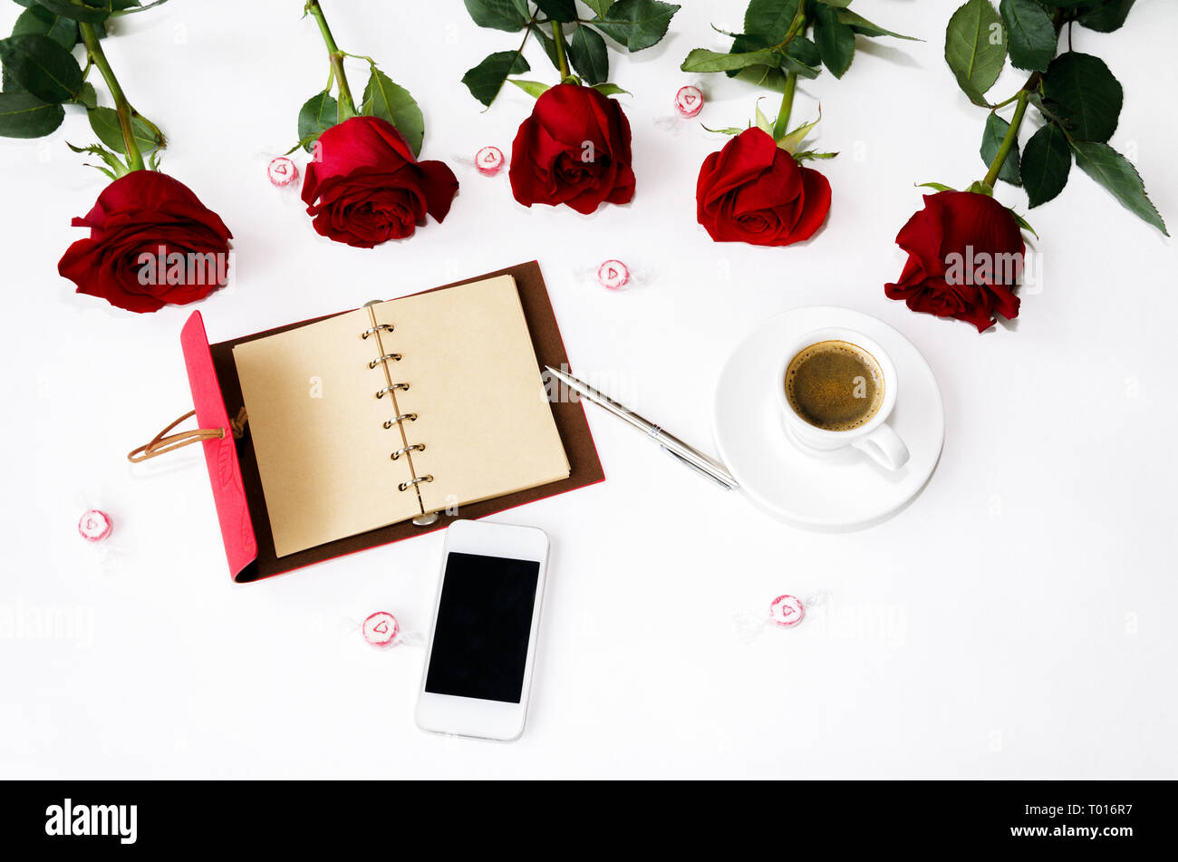 Notebook für das Schreiben mit einem Stift und einem Bouquet von roten Duftende Rosen auf einem hellen Hintergrund Stockfoto