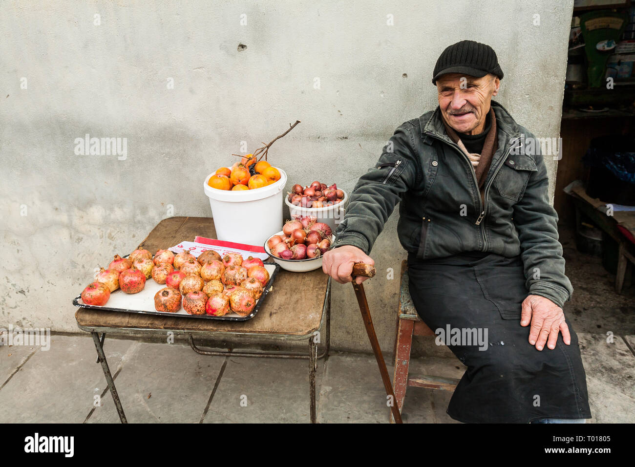 Signagi, Georgien - November 23, 2011: Der alte Mann verkauf Granatäpfel, Zwiebel und Persimmon auf einer Straße in Signagi, Georgien Stockfoto