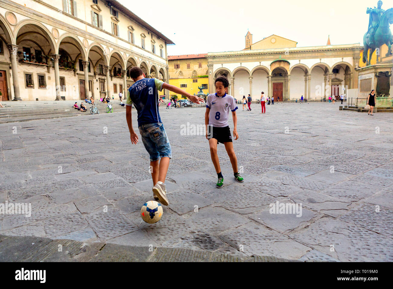Jungs im Teenageralter kick ein socerball rund um die Piazza della Santissima Annunziata in Florenz, in der Region Toskana, Italien. Stockfoto