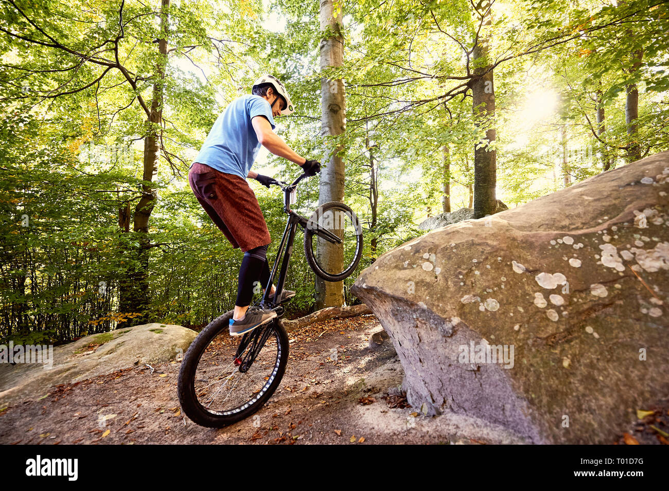 Junge portsman Radfahrer reiten auf der Rückseite Rad Trial Bike, mann Reiter balancing am Rande des Big Boulder im Wald im Sommer sonnigen Tag. Konzept o Stockfoto