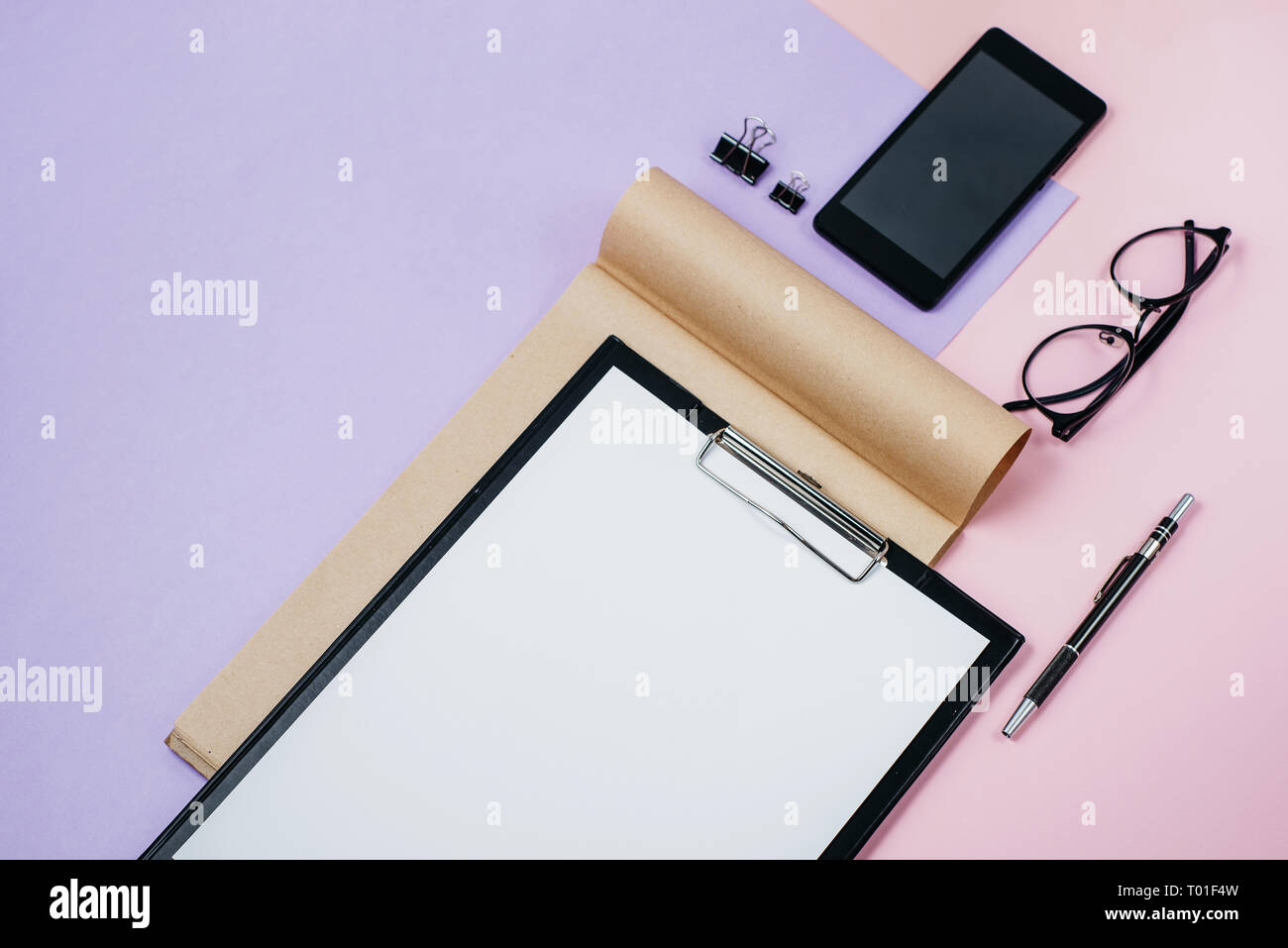 Mock up Arbeitsbereich mit leeren Clip Board, Bürobedarf, Kugelschreiber, Notizblock, auf rosa und violetten Hintergrund smartphone. Flach, Ansicht von oben, stilvolle weibliche c Stockfoto