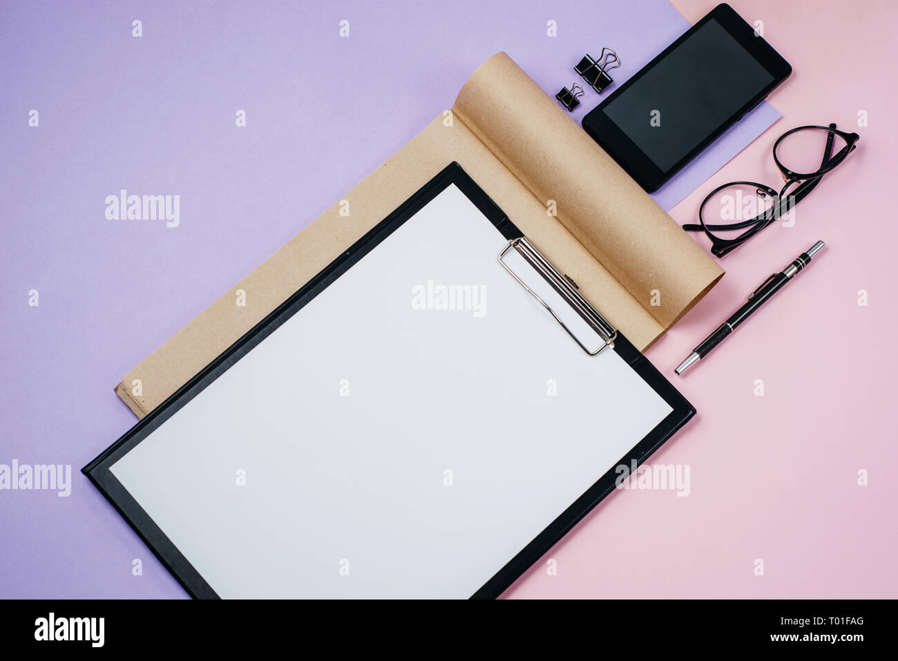 Flach, Ansicht von oben Bürotisch Schreibtisch. Mit leeren Clip Board, Bürobedarf, pen, Smartphone und Gläser auf rosa und violetten Hintergrund Arbeitsbereich. Blo Stockfoto