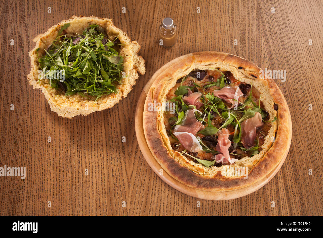 Pizza mit Speck und Vegetation serviert auf hölzernen Platte mit Petersilie Salat grüne Fleisch und Käse Stockfoto